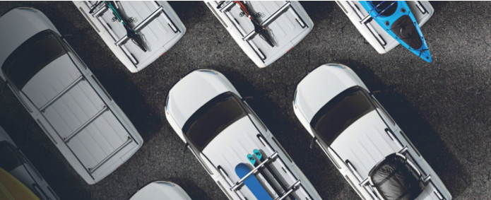 A top-down view of several vehicles outfitted with roof racks to carry bicycles, kayaks, skis and luggage.