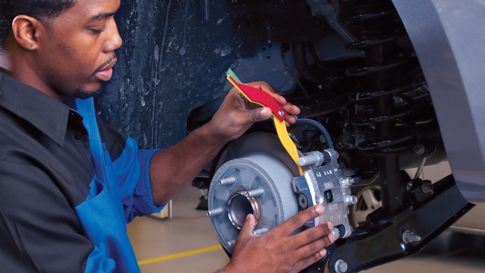 Mopar technician using gauge to measure brake pad thickness