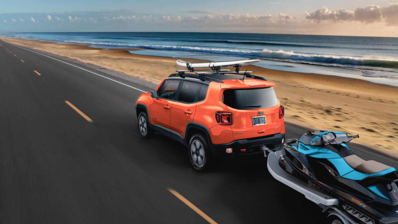2021 Mopar Renegade Latitude in Omaha Orange towing a jet ski on a coastal road