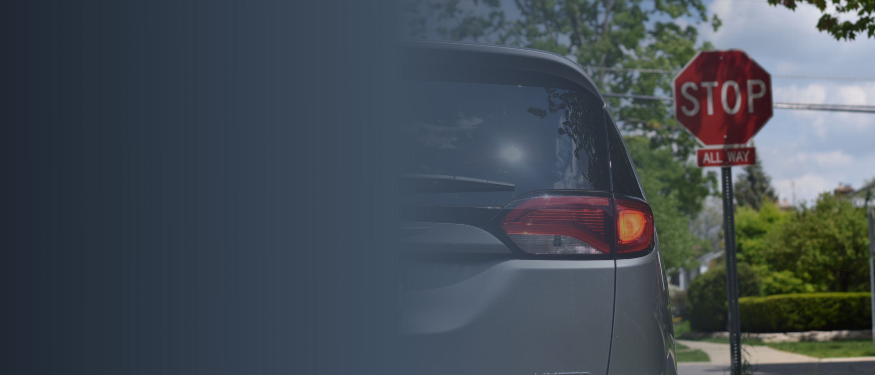 A 2022 Chrysler Pacifica at a stop sign with its brake lights illuminated.