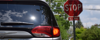 A 2022 Chrysler Pacifica at a stop sign with its brake lights illuminated.