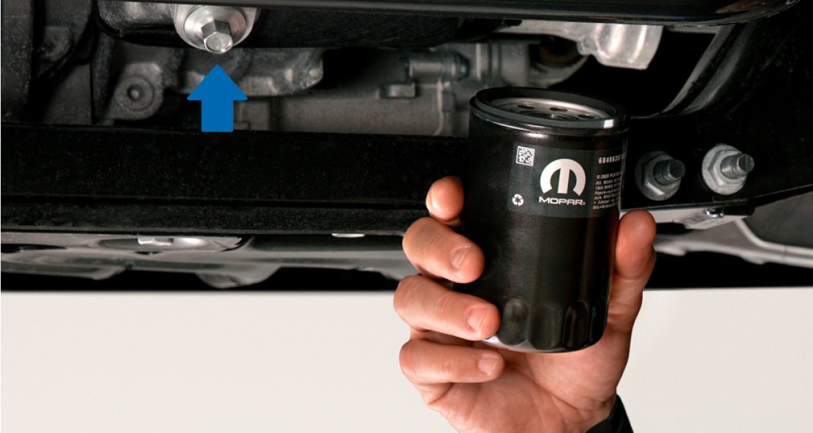 Hombre sosteniendo un filtro de aceite para motor Mopar a punto de instalarlo en una camioneta Ram