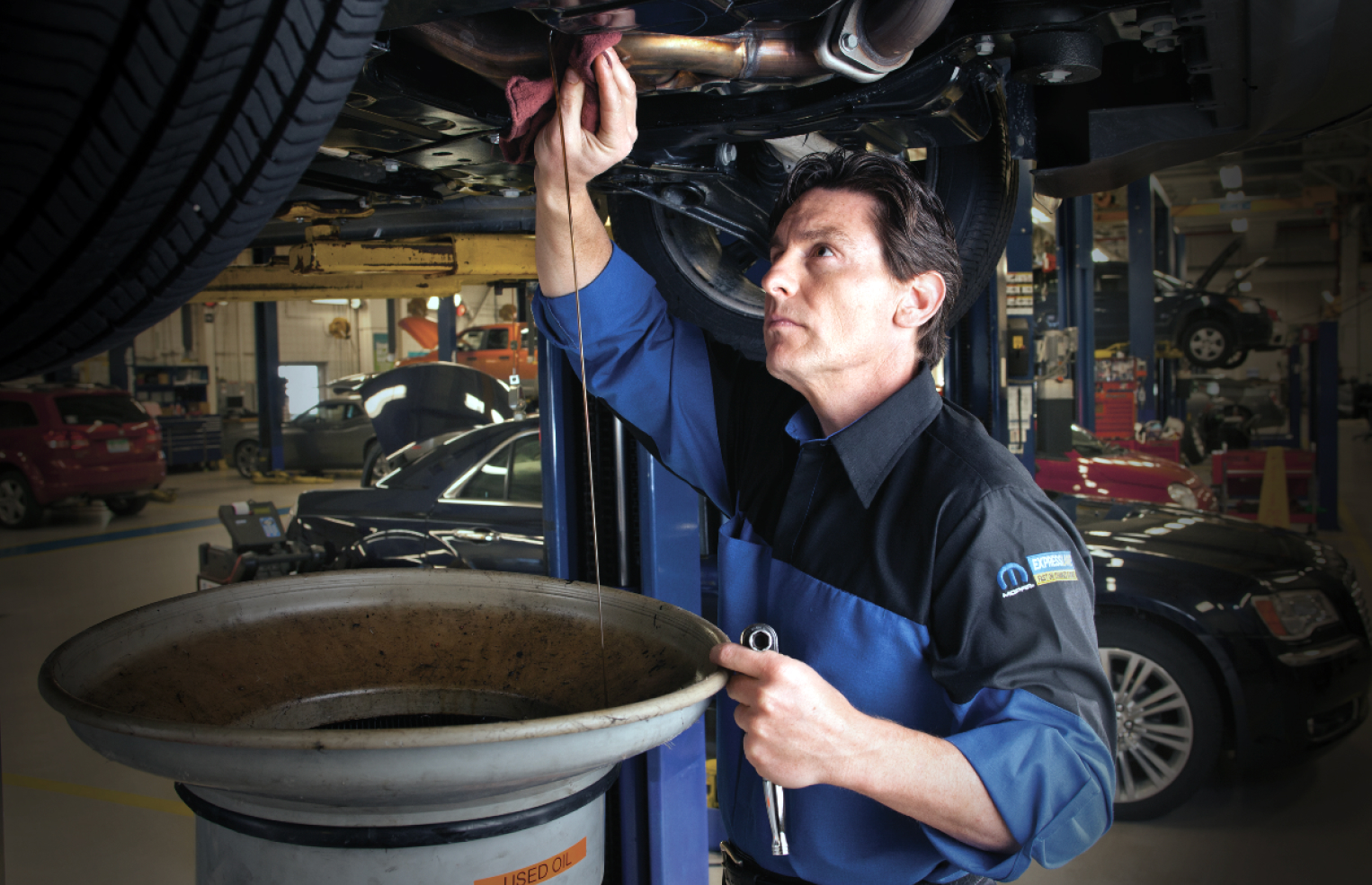 Un técnico de Mopar drenando el aceite de un vehículo durante un cambio de aceite