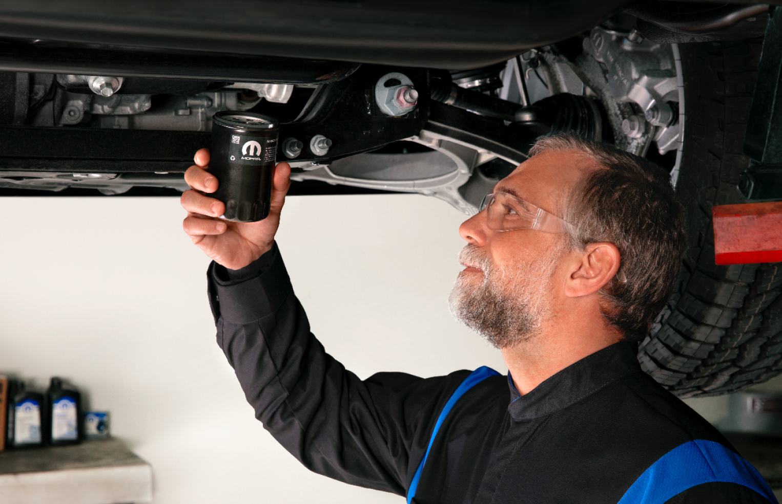 Hombre sosteniendo un filtro de aceite para motor Mopar a punto de instalarlo en una camioneta Ram