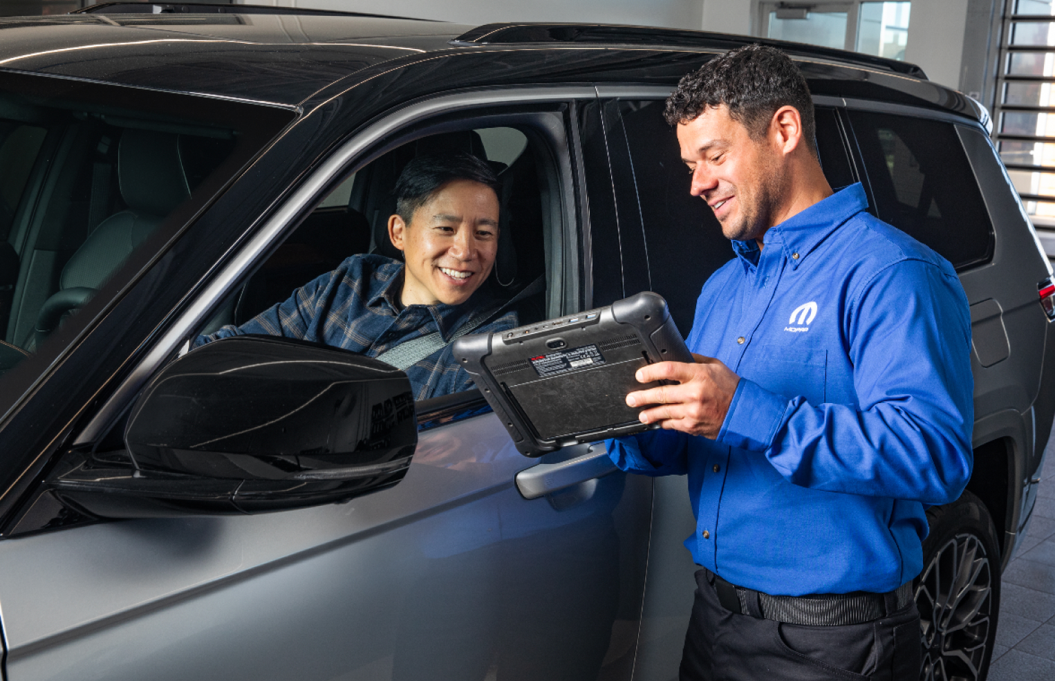 Un asesor de servicio le muestra algo a un cliente en una tablet en un Mopar Express Lane