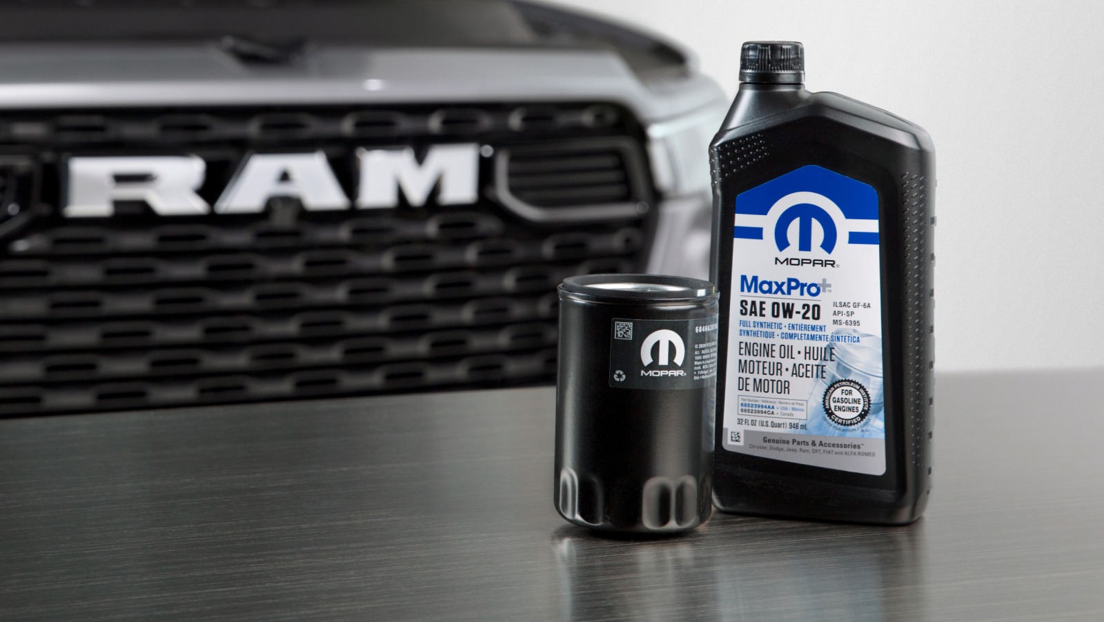 Aceite y filtro de aceite Mopar sobre una mesa frente a una camioneta Ram plateada