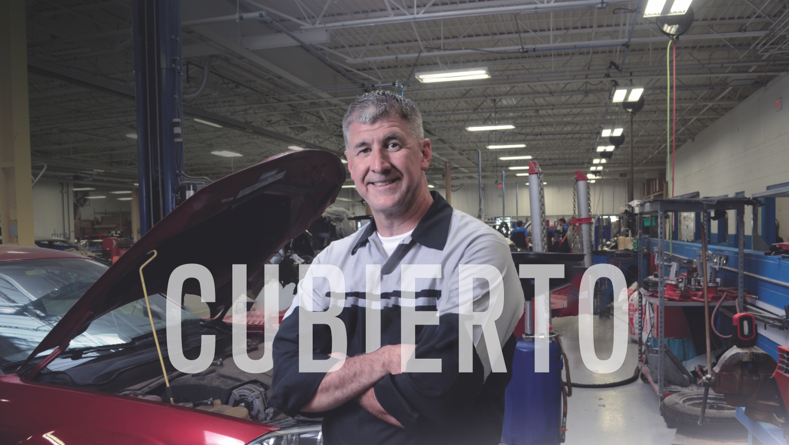 Un técnico de Mopar de pie, con los brazos cruzados, delante de un coche con el capó abierto, con la palabra "CUBIERTO" en blanco sobre la imagen.