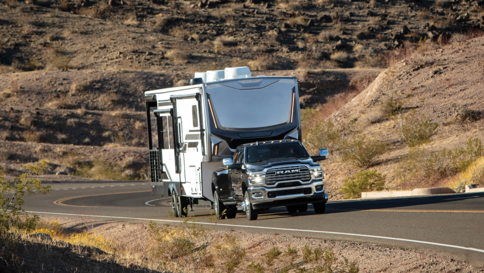 Modelo Limited 3500 2026 en color Diamond Black Crystal Pearl, remolcando una gran caravana cuesta arriba por un camino rural sinuoso