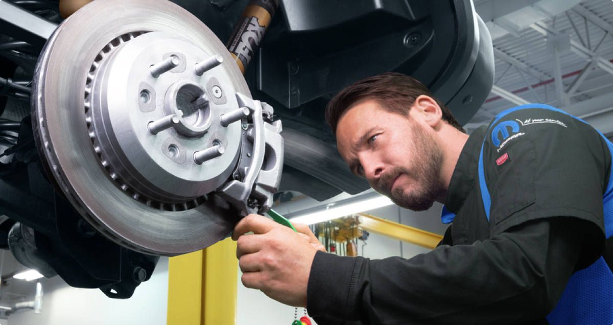 a mopar technician fixing car wheel in mopar garage